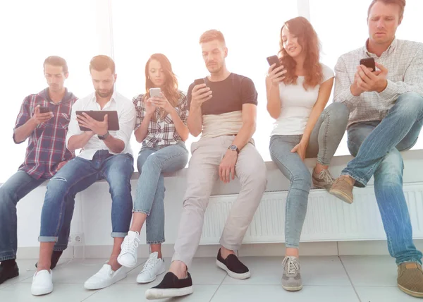 Junge Leute in lässiger Kleidung mit Gadgets — Stockfoto