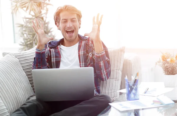 Feliz joven exitoso mirando a la computadora portátil en casa . — Foto de Stock