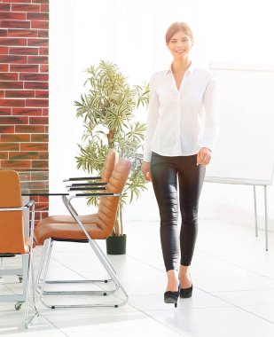 Gülümseyen genç bayan asistan ofiste dolaşıyor..