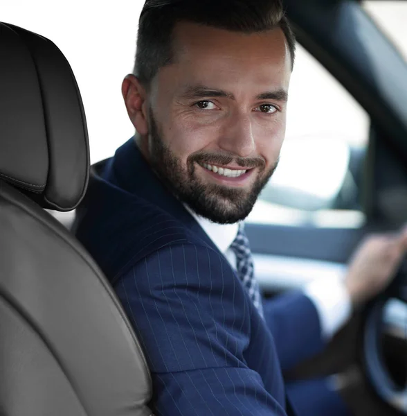 Bonito jovem sentado no banco da frente de um carro olhando para a câmera — Fotografia de Stock