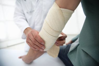 Orthopedist applying bandage onto patients hand in clinic clipart