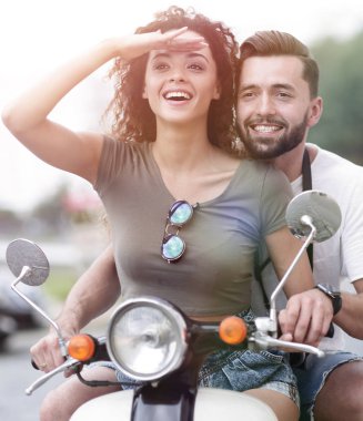 Güzel genç bir çift bir scooter sürme sırasında gülümsüyor