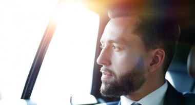 bir arabanın arka koltuğunda oturan işadamı