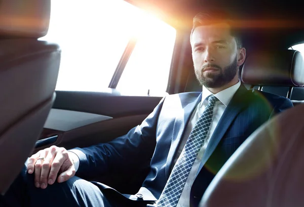 Úspěšný podnikatel, sedící na zadním sedadle auta — Stock fotografie
