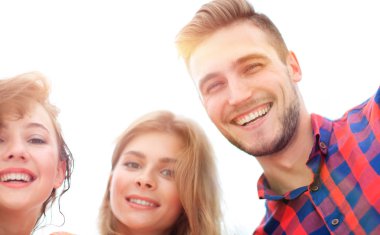 Beyaz arka planda gülümseyen üç genç insana yakın çekim