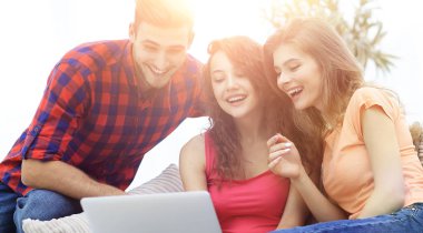 couc üzerinde oturan bir dizüstü ekran bakarak öğrenci grubu