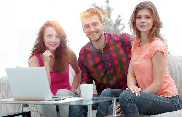 Group of students sitting on a couch behind a coffee table. — Stock Photo, Image