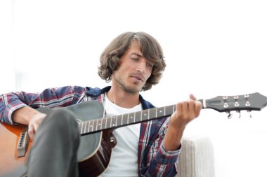 Yakışıklı adam evde kanepede gitar çalmaya