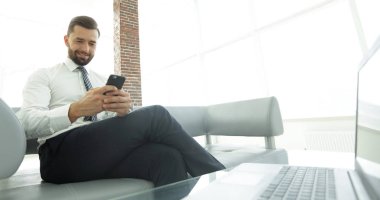 İşadamı ile modern bir ofis lobisinde oturan bir smartphone