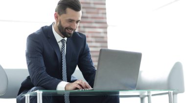 bir ofiste bir kanepede oturan dizüstü bilgisayar üzerinde çalışan iş adamı