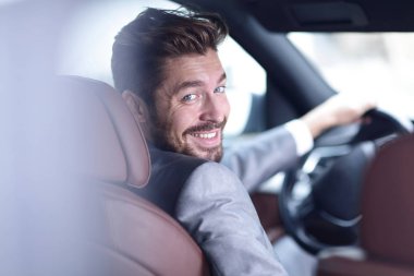 Başarılı bir adam prestijli bir arabanın direksiyonunda oturuyor.