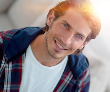 dizüstü bilgisayarda çalışan ve kameraya bakarak bir genç adam. Yukarıdan görüntülemek