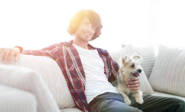 şık adam köpeğiyle kanepede oturan.