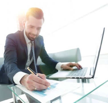 iş grafikleri ile bir dizüstü bilgisayarda çalışan Finans Yöneticisi