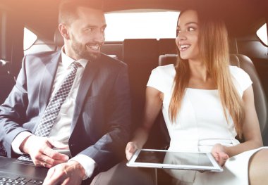 Genç iş adamları bir taksinin arka koltuğunda oturuyor.