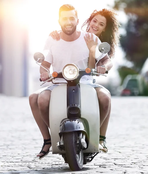 Happy young couple riding a scooter in the city on a sunny day — Stock Photo, Image