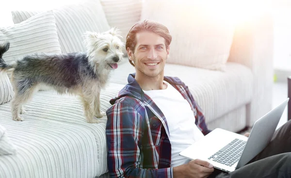 Erfolgreicher Kerl und sein Haustier in einem gemütlichen Wohnzimmer. — Stockfoto