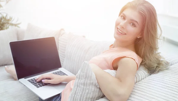 Bela jovem mulher trabalhando com laptop sentado no sofá e lo — Fotografia de Stock