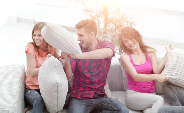 Group of friends playing pillow fight, sitting on the couch — Stock Photo, Image
