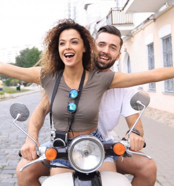 Güzel genç bir çift bir scooter sürme sırasında gülümsüyor