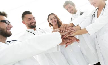 Doktorlar ve hemşireler tıbbi bir ekipte el ele tutuşuyorlar.