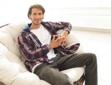 modern adam büyük bir rahat sandalyede oturuyor.