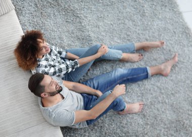 yeni bir oturma odasında bir halı üzerinde oturan yeni evli çift