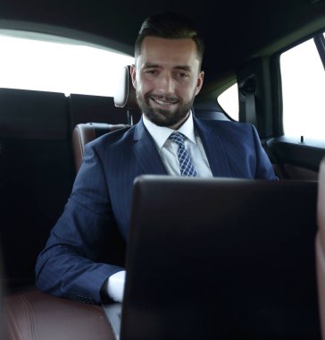 Bir arabanın arka koltuğunda oturan başarılı adam