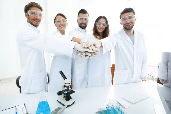 Equipe bem sucedida de jovens cientistas com as mãos apertadas juntas . — Fotografia de Stock