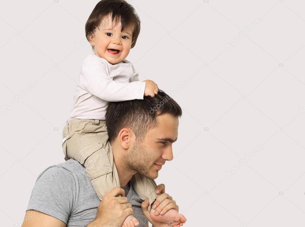 the little boy is sitting on the shoulders of Dad