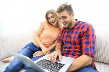 Mutlu modern çift internette sörf yapıyor ve evde dizüstü bilgisayarla çalışıyor.