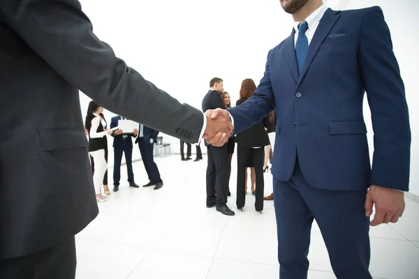 Nahaufnahme des Handschlags von Geschäftspartnern vor dem Hintergrund des Geschäftsteams — Stockfoto