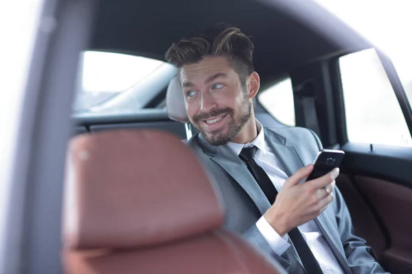 Nesmějící se obchodník sedí na zadním sedadle ve svém autě — Stock fotografie