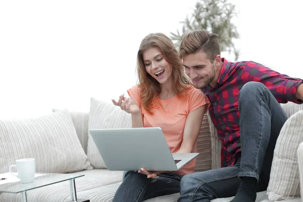 Young man with his girlfriend looking at the laptop sitting on the sofa. — Stock Photo, Image