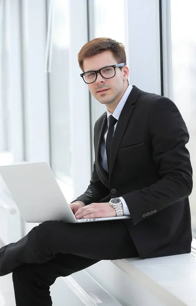 Jeune professionnel avec ordinateur portable sur fond de fenêtre de bureau — Photo