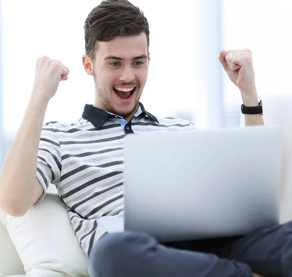 Happy man with laptop sitting on the couch Stock Picture