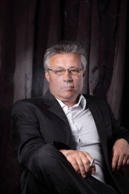 bir sandalyede oturan bir sigara ile üst düzey iş adamı