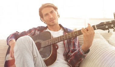 oturma odasında kanepede oturup gitar ile Modern adam.