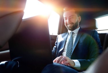 Arabada otururken diz üstü üzerinde çalışan iş adamı