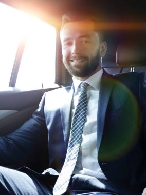 bir arabanın arka koltuğunda oturan işadamı