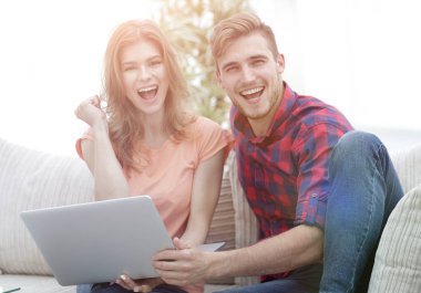 Genç çift sevinir, açık önünde kanepede oturan 