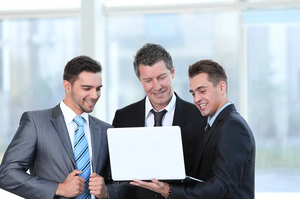 Üzleti partnerek egy laptop áll az előtérben a Hivatal. — Stock Fotó