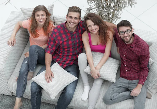 Grupo de amigos com almofadas, sentado no sofá — Fotografia de Stock