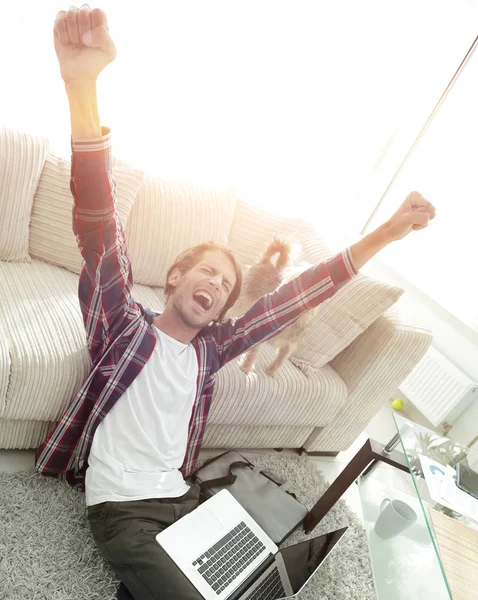 Happy guy with laptop jubilant in spacious living room. — Stock Photo, Image