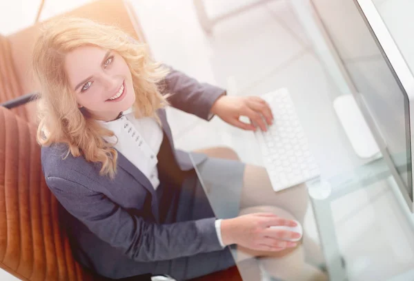 Glimlachende zakenvrouw zitten achter een bureau — Stockfoto