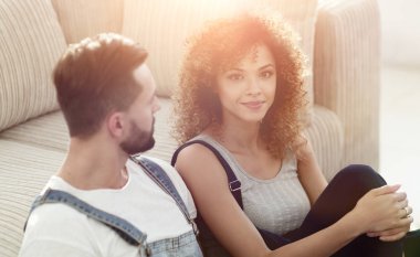 Yeni evliler yeni bir dairede kanepede oturuyor..