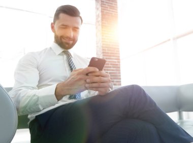 İşadamı ile modern bir ofis lobisinde oturan bir smartphone