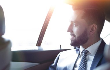 Bir arabanın arka koltuğunda oturan gülümseyen iş adamı