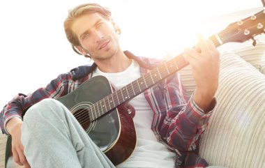 oturma odasında kanepede oturup gitar ile Modern adam.