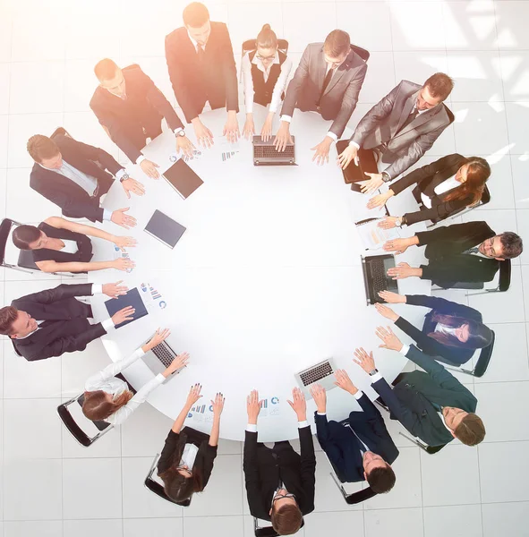 Grupo de empresários sentados à mesa redonda, e colocando as palmas das mãos sobre a mesa — Fotografia de Stock